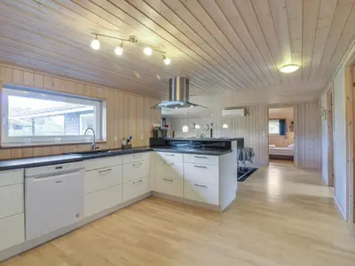 a kitchen with white cabinets and a wooden ceiling at Holiday Home Susan - 600m from the sea by Interhome in Løkken