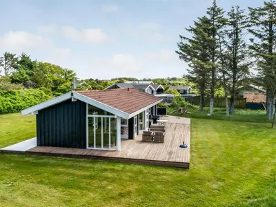 a small house with a deck in a yard at Holiday Home Klakke - 900m from the sea by Interhome in Løkken