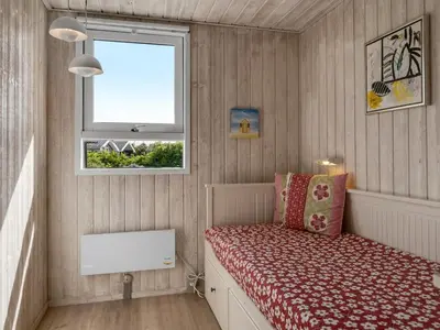 a small bedroom with a bed and a window at Holiday Home Klakke - 900m from the sea by Interhome in Løkken