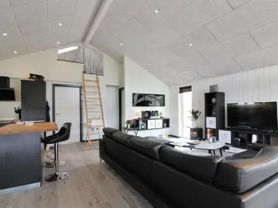a living room with a black couch and a television at Holiday Home Aldina - 1-5km from the sea by Interhome in Løkken