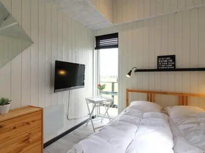 a bedroom with a bed and a tv on a wall at Holiday Home Aldina - 1-5km from the sea by Interhome in Løkken
