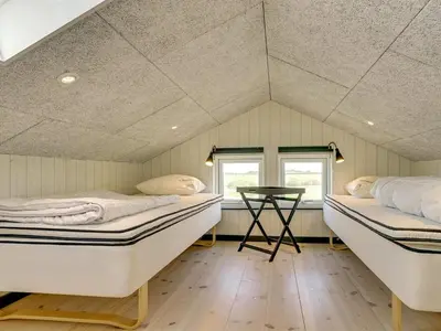 a room with two beds and a table in it at Holiday Home Aldina - 1-5km from the sea by Interhome in Løkken