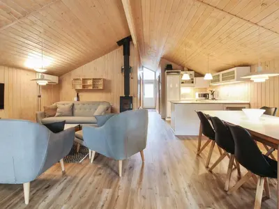 a living room with a table and chairs and a kitchen at Holiday Home Elsemaria - 1-3km from the sea by Interhome in Løkken
