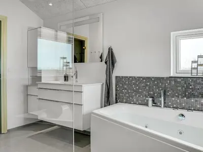 a white bathroom with a tub and a sink at Holiday Home Fegge - 1-5km from the sea by Interhome in Løkken