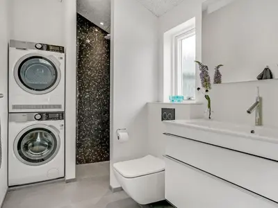 a white bathroom with a sink and a washing machine at Holiday Home Fegge - 1-5km from the sea by Interhome in Løkken