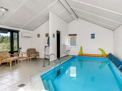 a swimming pool in a living room with a table and chairs at Holiday Home Lempi - 300m from the sea by Interhome in Løkken