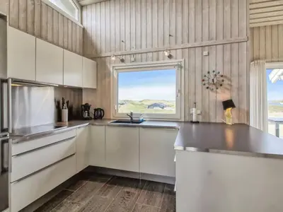 a kitchen with white cabinets and a window at Holiday Home Romil - 350m from the sea by Interhome in Løkken