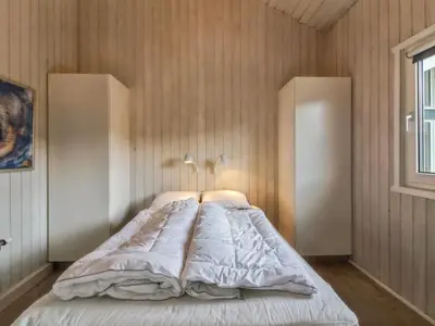 a bedroom with a large bed with two lamps on it at Holiday Home Romil - 350m from the sea by Interhome in Løkken