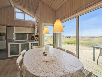 a kitchen and dining room with a table and chairs at Holiday Home Romil - 350m from the sea by Interhome in Løkken