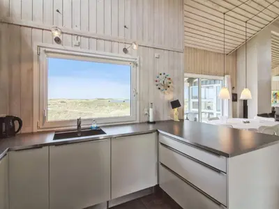 a kitchen with a sink and a large window at Holiday Home Romil - 350m from the sea by Interhome in Løkken