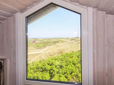 a window in a room with a view of a field at Holiday Home Romil - 350m from the sea by Interhome in Løkken