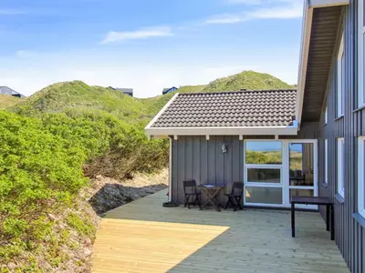 a house with a deck with a table and chairs at Holiday Home Romil - 350m from the sea by Interhome in Løkken