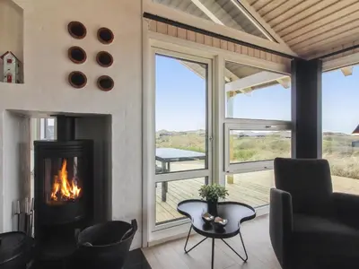 a living room with a fireplace and a view of a deck at Holiday Home Romil - 350m from the sea by Interhome in Løkken