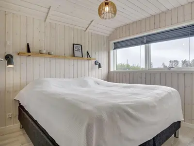 a white bed in a room with a window at Holiday Home Ina - 1-2km from the sea by Interhome in Løkken