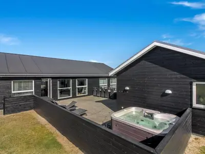 a black house with a hot tub in the backyard at Holiday Home Edgar - 1-5km from the sea by Interhome in Løkken