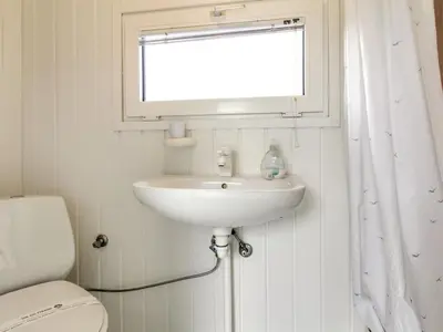 a bathroom with a sink and a window and a toilet at Holiday Home Gitten - 600m from the sea by Interhome in Løkken