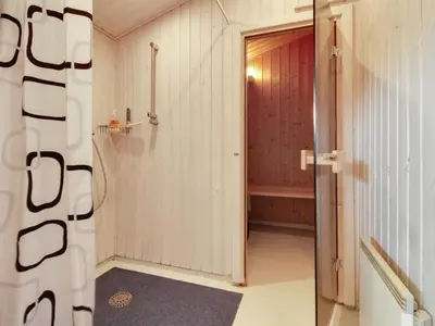 a bathroom with a shower and a red door at Holiday Home Gitten - 600m from the sea by Interhome in Løkken