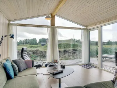 a living room with a couch and a large window at Holiday Home Marino - 480m from the sea by Interhome in Løkken