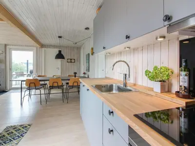 a kitchen with a sink and a table with chairs at Holiday Home Marino - 480m from the sea by Interhome in Løkken