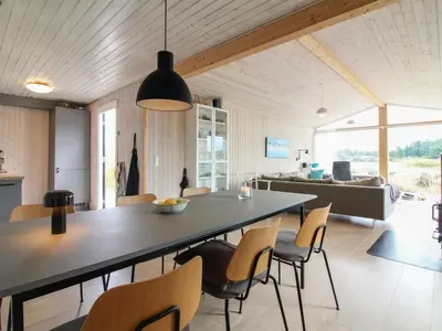 a dining room and living room with a table and chairs at Holiday Home Marino - 480m from the sea by Interhome in Løkken