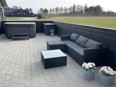 a patio with a couch and a table and a grill at Holiday Home Dwerg - 1-5km from the sea by Interhome in Løkken