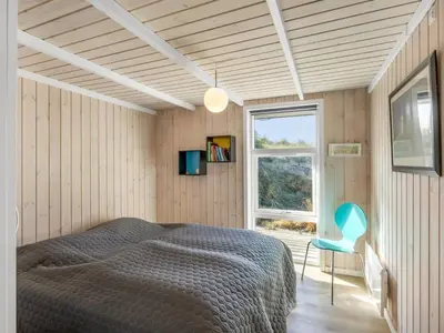 a bedroom with a bed and a blue chair at Holiday Home Elna - 400m from the sea by Interhome in Løkken