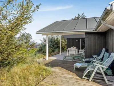 a deck with chairs and a table on a house at Holiday Home Elna - 400m from the sea by Interhome in Løkken