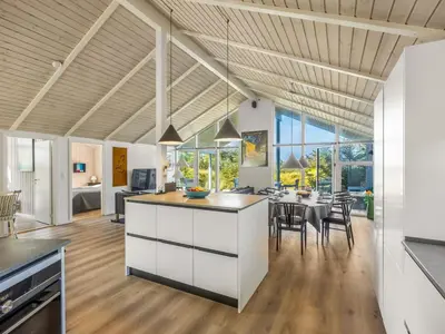 a kitchen and dining room with white cabinets and a table at Holiday Home Elna - 400m from the sea by Interhome in Løkken