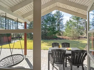 a screened in porch with a table and chairs at Holiday Home Herwarth - 3-3km from the sea by Interhome in Blokhus
