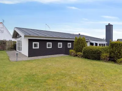 a black and white house with a yard at Holiday Home Frethi - 350m from the sea by Interhome in Blokhus