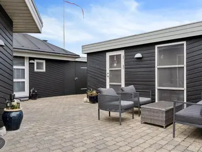 a patio with chairs and a table and a building at Holiday Home Frethi - 350m from the sea by Interhome in Blokhus