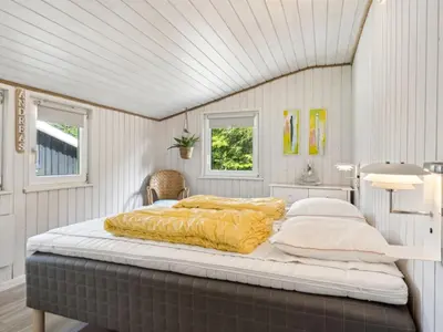 a bedroom with a large bed with yellow sheets at Holiday Home Marli - 700m from the sea by Interhome in Blokhus
