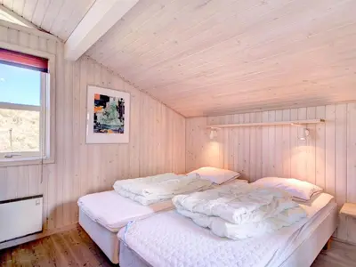 a bedroom with two beds in a room with wooden walls at Holiday Home Nedelko - 250m from the sea by Interhome in Blokhus