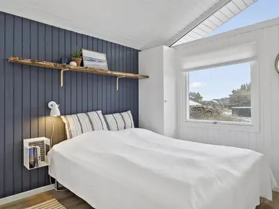 a bedroom with a large white bed and a window at Holiday Home Yessica - 300m from the sea by Interhome in Løkken