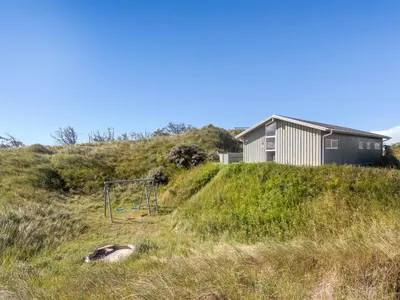 a house on top of a hill with a playground at Holiday Home Kalervo - 100m from the sea by Interhome in Pandrup