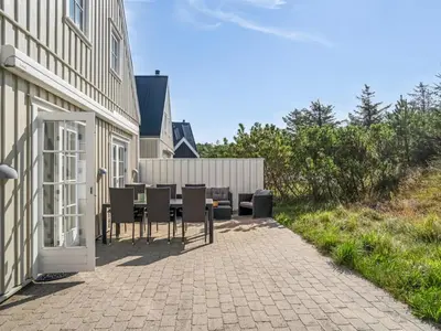a patio with chairs and a table next to a building at Holiday Home Ingmarie - 1km from the sea by Interhome in Blokhus