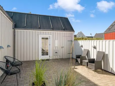 a patio with two chairs and a building at Holiday Home Ingmarie - 1km from the sea by Interhome in Blokhus