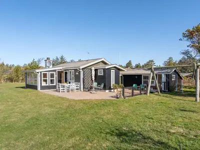 a house with a playground in the yard at Holiday Home Ingebritt - 1-5km from the sea by Interhome in Blokhus