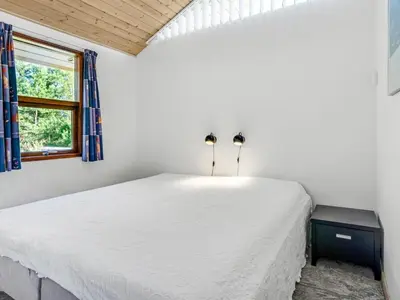 a bedroom with a white bed and a window at Holiday Home Vetle - 2-8km from the sea by Interhome in Blokhus