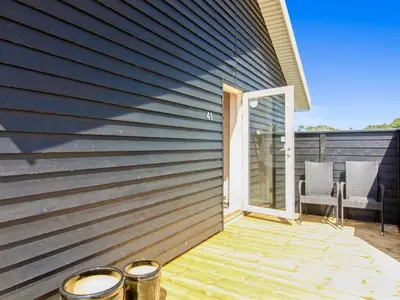 a wooden deck with a door and a patio at Holiday Home Elenore - 900m from the sea by Interhome in Løkken