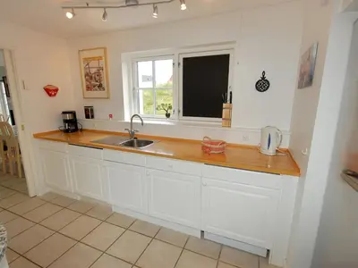 a kitchen with white cabinets and a sink and a window at Holiday Home Stine - 1km from the sea by Interhome in Blokhus