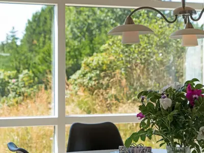 a table with a vase of flowers in front of a window at Holiday Home Felizia - 2-5km from the sea by Interhome in Blokhus