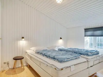 a white bedroom with a large bed with blue sheets at Holiday Home Wiebke - 200m from the sea by Interhome in Blokhus