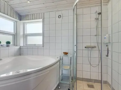 a white bathroom with a tub and a shower at Holiday Home Ninna - 1km from the sea by Interhome in Blokhus