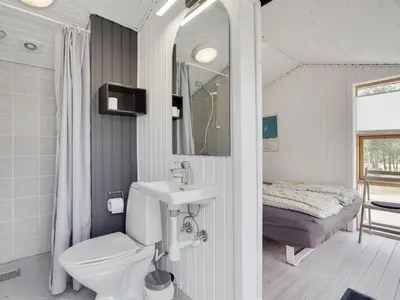 a bathroom with a toilet and a sink and a bed at Holiday Home Ninna - 1km from the sea by Interhome in Blokhus