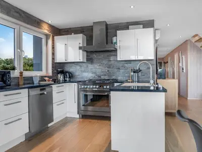 a kitchen with white cabinets and stainless steel appliances at Holiday Home Skamhals - 700m from the sea by Interhome in Blokhus