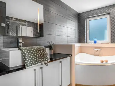 a bathroom with a tub and a sink at Holiday Home Skamhals - 700m from the sea by Interhome in Blokhus