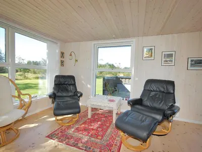 a room with two chairs and a table and windows at Holiday Home Tomke - 1-7km from the sea by Interhome in Blokhus