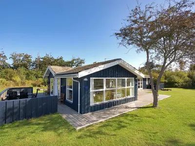 a small blue house with a deck in a yard at Holiday Home Tomke - 1-7km from the sea by Interhome in Blokhus