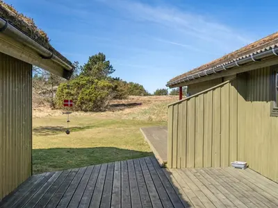 a wooden walkway between two buildings with a yard at Holiday Home Alfrik - 900m from the sea by Interhome in Blokhus